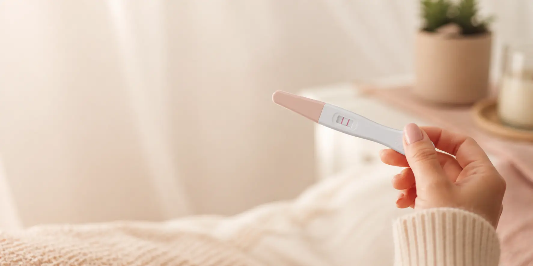 Positive pregnancy test held in hand with two lines visible, close-up at home, early pregnancy result concept